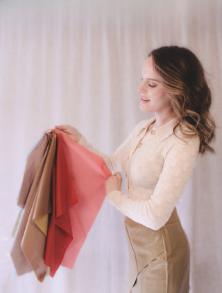 Personal stylist Mylène Amelie demonstrating colour analysis draping with warm seasonal colour fabrics to identify a client’s most flattering palette during a styling consultation in Calgary and virtual sessions worldwide.