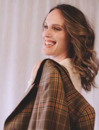 Personal stylist Mylene Amelie smiling while holding a plaid jacket, representing wardrobe styling and outfit selection for women seeking personal styling services in Calgary and online.