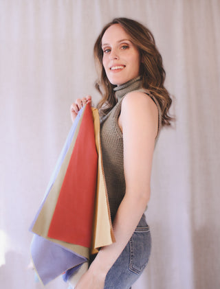 Personal stylist Mylène Amelie holding multiple colour analysis fabric drapes representing different seasonal palettes used during professional colour analysis consultations in Calgary and virtual styling services worldwide.